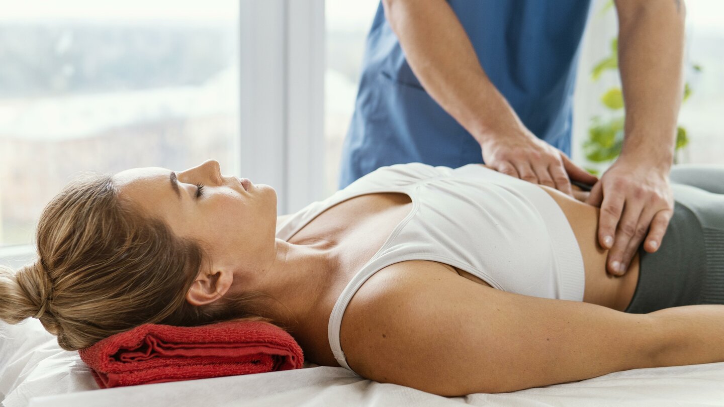 Front view of male osteopathic therapist checking female patient s abdomen