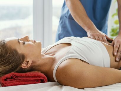 Front view of male osteopathic therapist checking female patient s abdomen