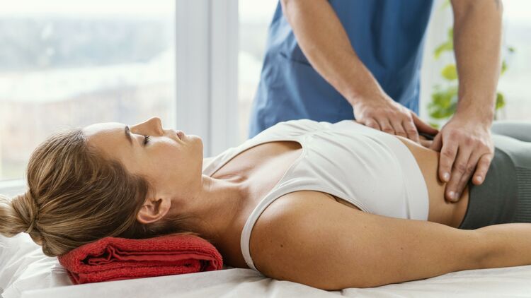 Front view of male osteopathic therapist checking female patient s abdomen